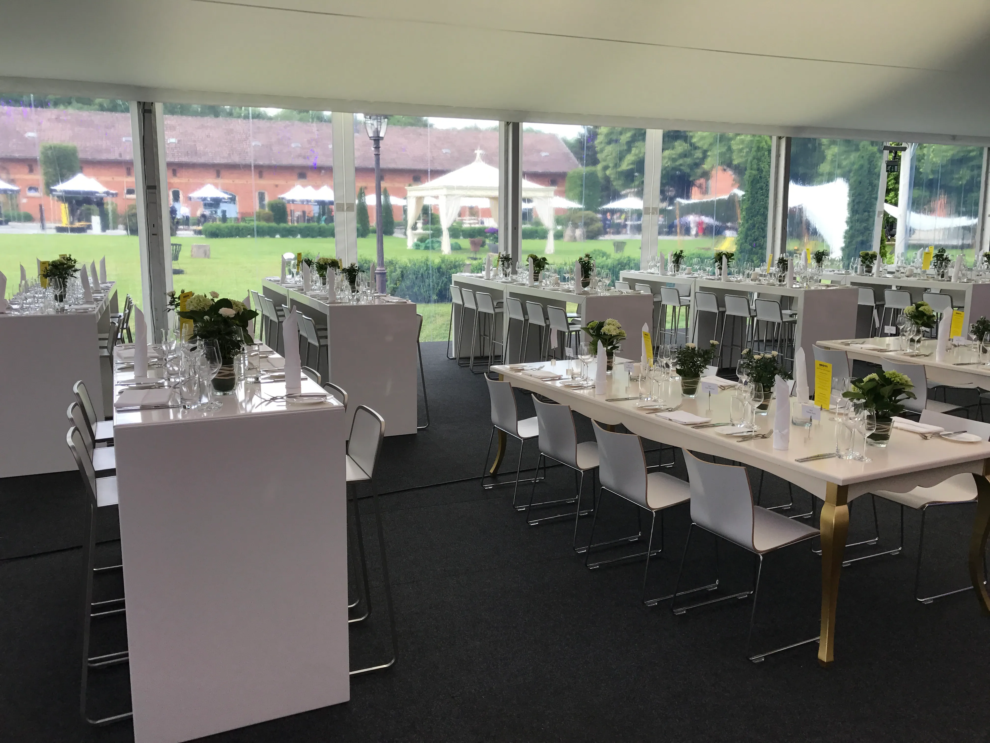 Elegant eingedeckte lange Tafeln in lichtem Veranstaltungszelt