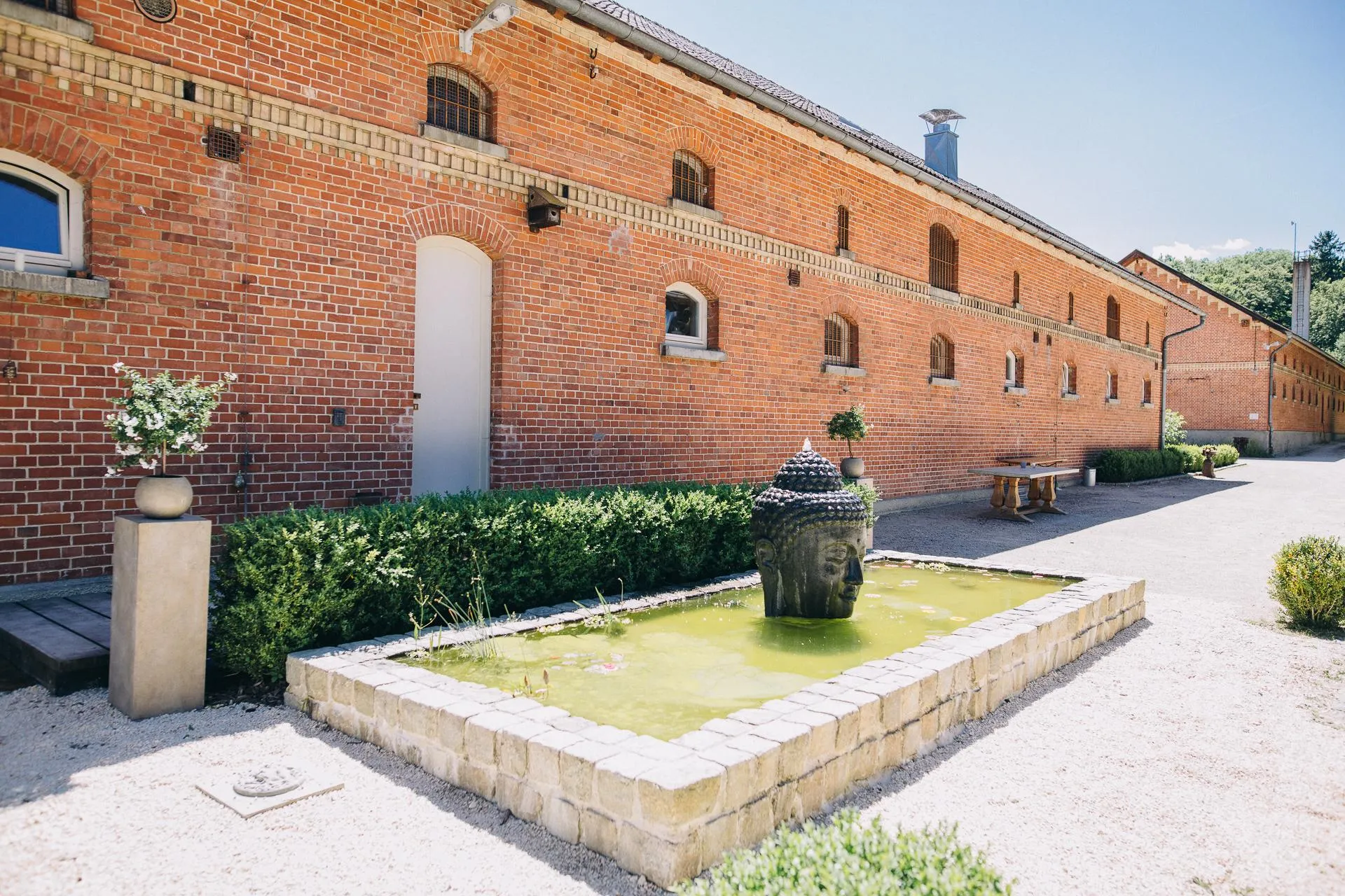 Die lange Backsteinfassade der historischen Stallungen mit Brunnen im Kieshof